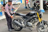 Salah satu anggota Sat Lantas Polres Parepare memperlihatkan sepeda motor yang diamankan petugas karena menggunakan knalpot brong