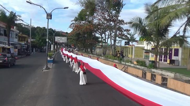 Sejumlah ibu-ibu mengangkat bendera sepanjang 180 meter yang diarak sejauh 7 kilometer