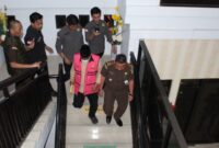 Tersangka inisial HM megenakan rompi berwarna pink terlihat menuruni anak tangga dengan pengawalan ketat dari pihak Kejari Parepare, usai menjalani pemeriksaan 