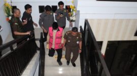 Tersangka inisial HM megenakan rompi berwarna pink terlihat menuruni anak tangga dengan pengawalan ketat dari pihak Kejari Parepare, usai menjalani pemeriksaan 