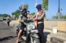 Danyon B Pelopor Sat Brimob Polda Sulsel, Kompo. Dr. Ramli sedang memasangkan bendera merah putih berukuran kecil kepengendara roda saat membagi-bagikan bendera dalam rangka semarak HUT ke-81 Kemerdekaan RI