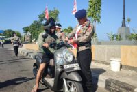 Danyon B Pelopor Sat Brimob Polda Sulsel, Kompo. Dr. Ramli sedang memasangkan bendera merah putih berukuran kecil kepengendara roda saat membagi-bagikan bendera dalam rangka semarak HUT ke-81 Kemerdekaan RI