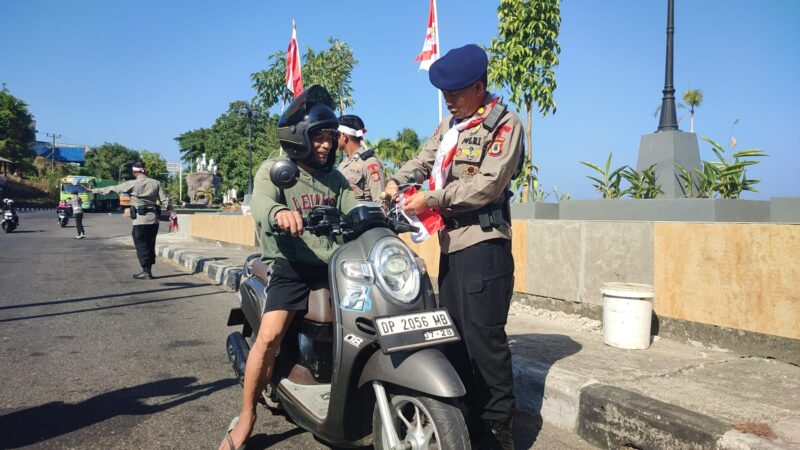 Danyon B Pelopor Sat Brimob Polda Sulsel, Kompo. Dr. Ramli sedang memasangkan bendera merah putih berukuran kecil kepengendara roda saat membagi-bagikan bendera dalam rangka semarak HUT ke-81 Kemerdekaan RI