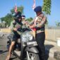 Danyon B Pelopor Sat Brimob Polda Sulsel, Kompo. Dr. Ramli sedang memasangkan bendera merah putih berukuran kecil kepengendara roda saat membagi-bagikan bendera dalam rangka semarak HUT ke-81 Kemerdekaan RI