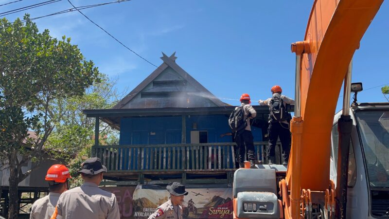 Tim SAR Sat Brimob Batalyon B Pelopor Polda Sulsel, memadamkan api yang menyambar salah satu rumah warga akibat kebakaran lahan